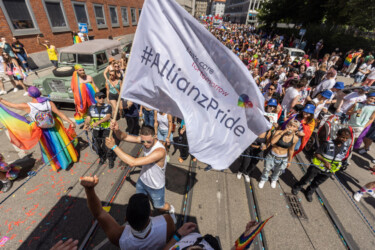 Foto vom CSD, Fahne mit dem Schriftzug "Let's care for tomorrow. #AllianzPride" wird geschwenkt.