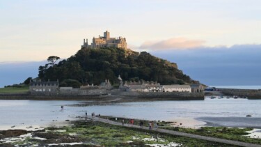 Auf der Gezeiteninsel St. Michaels Mount in Cornwall erhebt sich eine historische Burg vor einem teils bewölkten Himmel.