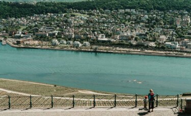 Zwei Personen stehen vor dem Rhein. Dahinter ist eine Stadt zu sehen