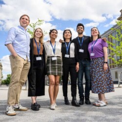 6 Studierende stehen lächelnd vor der ESMT