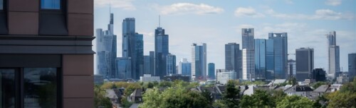 Die Skyline von Frankfurt am Main. Im Vordergrund eine Hausfassade.
