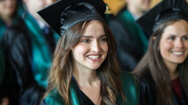 Eine Absolventin mit Talar und Graduiertenhut lächelt