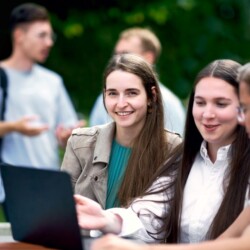 Studierende der HHL Leipzig sitzen zusammen vor einem Laptop.