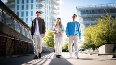 Drei Studierende laufen gemeinsam über eine Brücke