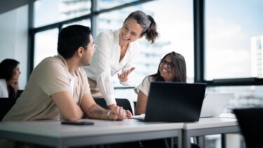 Eine Dozentin erklärt einem Studenten und einer Studentin etwas.