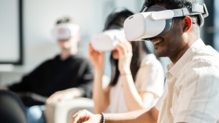 Drei Studierende sitzen mit VR-Brillen in einem Seminarraum.