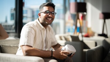 Ein Student hält eine VR-Brille in der Hand und lächelt.