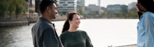 Drei Studierende stehen am Wasser und unterhalten sich