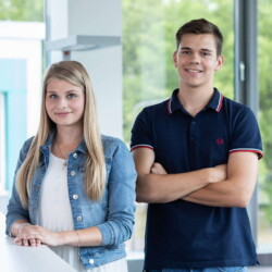 Eine Studentin und ein Student schauen in die Kamera.