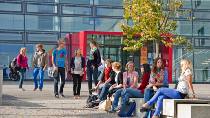 Studierende sitzen auf dem Campus und unterhalten sich