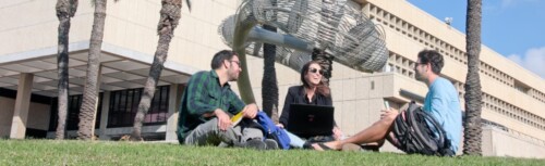Studierende sitzen auf grüner Wiese auf Campus der Tel Aviv University