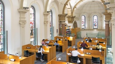 Bibliothek der UCD Smurfit School. Ein Raum mit Gewölbe und vielen Holztischen zum Arbeiten.