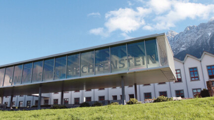Der Campus der Universität Liechtenstein. Blauer Himmel im Hintergrund Berge.