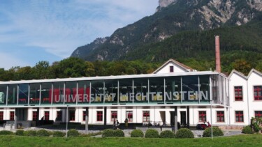 Das Hauptgebäude der Universität Liechtenstein am Fuß eines Berges.