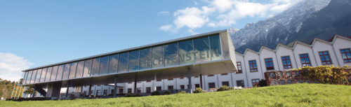 Der Campus der Universität Liechtenstein. Blauer Himmel im Hintergrund Berge.