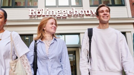 Studenten laufen vor einem Gebäude der University of Groningen