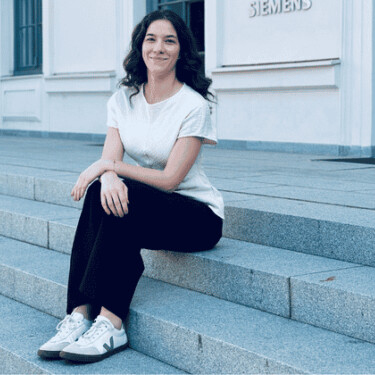 Louann sitzt auf einer Treppe vor einem Siemens-Gebäude