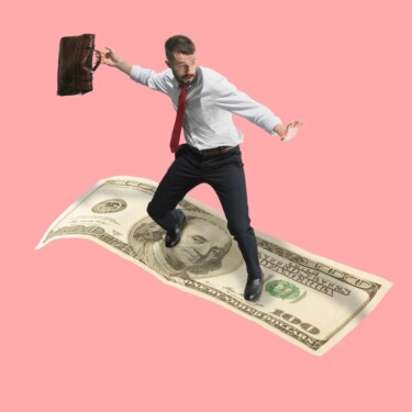 Ein junger Mann im Business-Dress surft auf einem Dollarschein