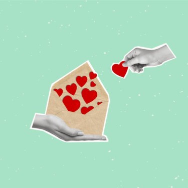 Hand hält einen Brief. Er ist offen und Herzen sind zu sehen. Andere Hand nimmt ein Herz heraus.