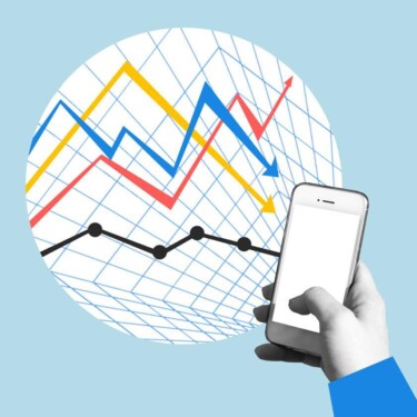 Hand hält Handy. Im Hintergrund ist eine Statistik zu sehen, die von Finanzen handelt.