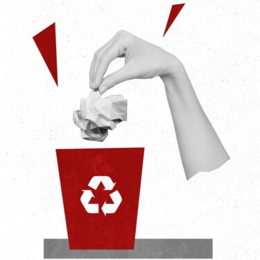 Hand wirft ein zerknülltes Stück Papier in einen Mülleimer, auf dem ein Recycling-Symbol angebracht ist.