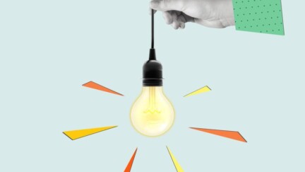 Eine Hand hält eine leuchtende Glühbirne in der Hand, die an einem Kabel hängt.