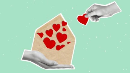 Hand hält einen Brief. Er ist offen und Herzen sind zu sehen. Andere Hand nimmt ein Herz heraus.