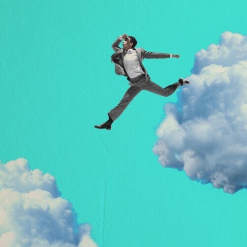 Ein Geschäftsmann springt wagemutig von einer Wolke zu einer anderen.