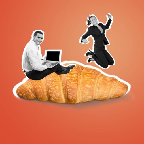 Ein riesiges Croissant, auf dem ein Mann mit Laptop im Scheidersitz sitzt. Im HIntergrund springt eine Frau,