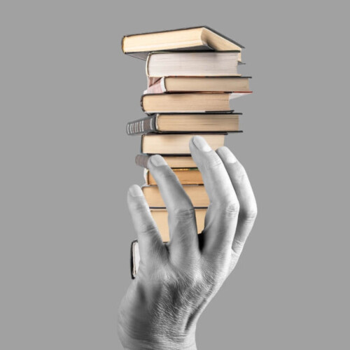 Eine Hand hält einen Stapel Bücher.