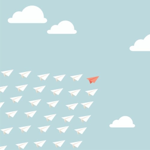 Weiße Papierflieger fliegen einem roten Papierflieger hinterher