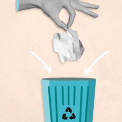 Hand wirft ein zerknülltes Stück Papier in einen Mülleimer, auf dem ein Recycling-Symbol angebracht ist.