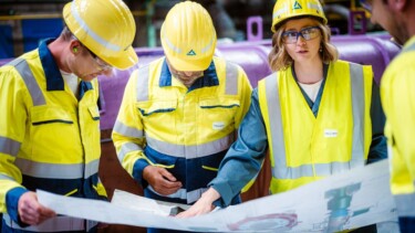 Vier Mitarbeitende besprechen einen Plan in der Produktionshalle