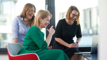 Drei Frauen von BDO schauen auf Laptop und lachen.