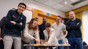 Mitarbeitende stehen zusammen und lachen.