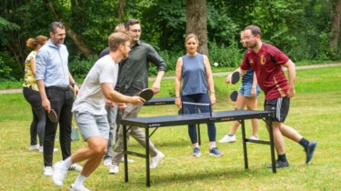 Mitarbeitende rennen um eine Tischtennisplatte herum