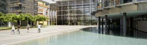 Das Firmengelände der HUK-Coburg mit einem künstlichen See und Fahnen im Hintergrund.