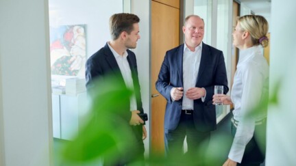 Zwei Mitarbeiter und eine Mitarbeiterin von Horn & Company unterhalten sich auf dem Gang.