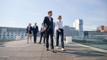 Mitarbeiter:innen von Horn & Company laufen über eine Dachterrasse.