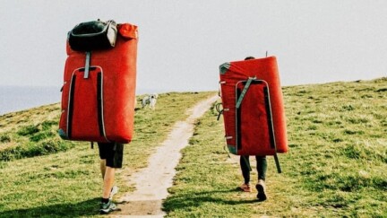 Zwei Menschen laufen auf Feldweg neben dem Meer.