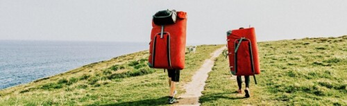 Zwei Menschen laufen auf Feldweg neben dem Meer.