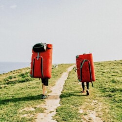 Zwei Menschen laufen auf Feldweg neben dem Meer.