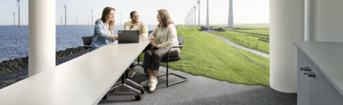 Zwei Frauen der ﻿KfW IPEX-Bank stehen vor einer Windturbine.