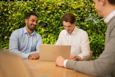 Drei Männer arbeiten zusammen an einem Laptop