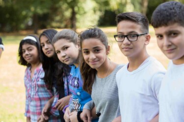 Sechs Kinder stehen in einer Reihe und schauen seitlich in die Kamera.