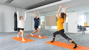 Zwei Männer und eine Frau machen gemeinsam Yoga.