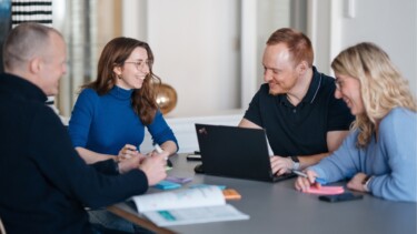 Mitarbeitende von undconsorten sitzen am Tisch und arbeiten gemeinsam.