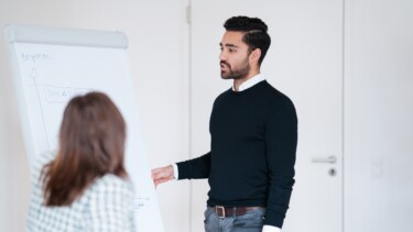 Ein Mann steht an einer Flipchart und erklärt.