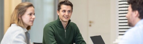 Mitarbeitende von undconsorten sitzen am Tisch und diskutieren.