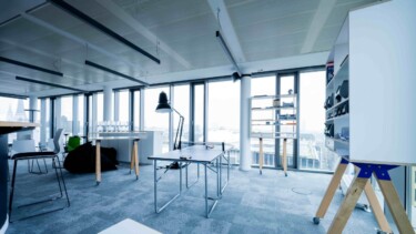 Helles Büro mit großen Fenstern und Arbeitsplätzen.